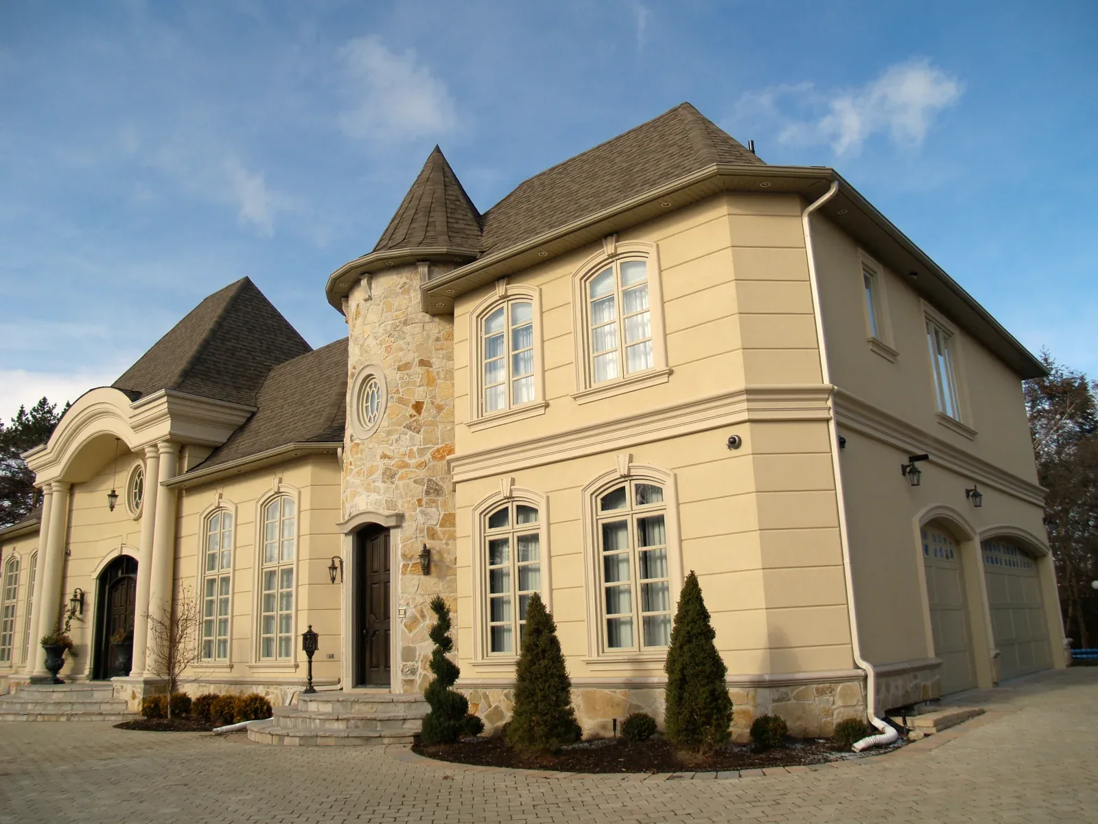Stone-and-stucco residence with an arched entrance and two framed upper windows